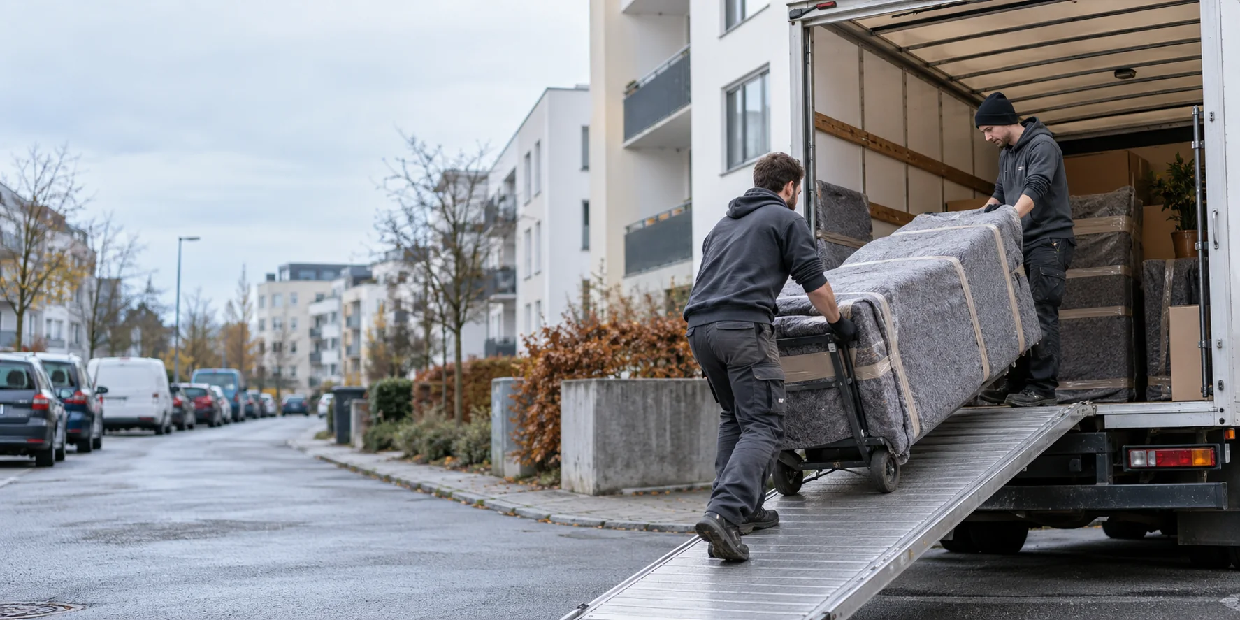 Zwei Umzugsprofis laden geschützte Möbel in einen neutralen Möbelwagen